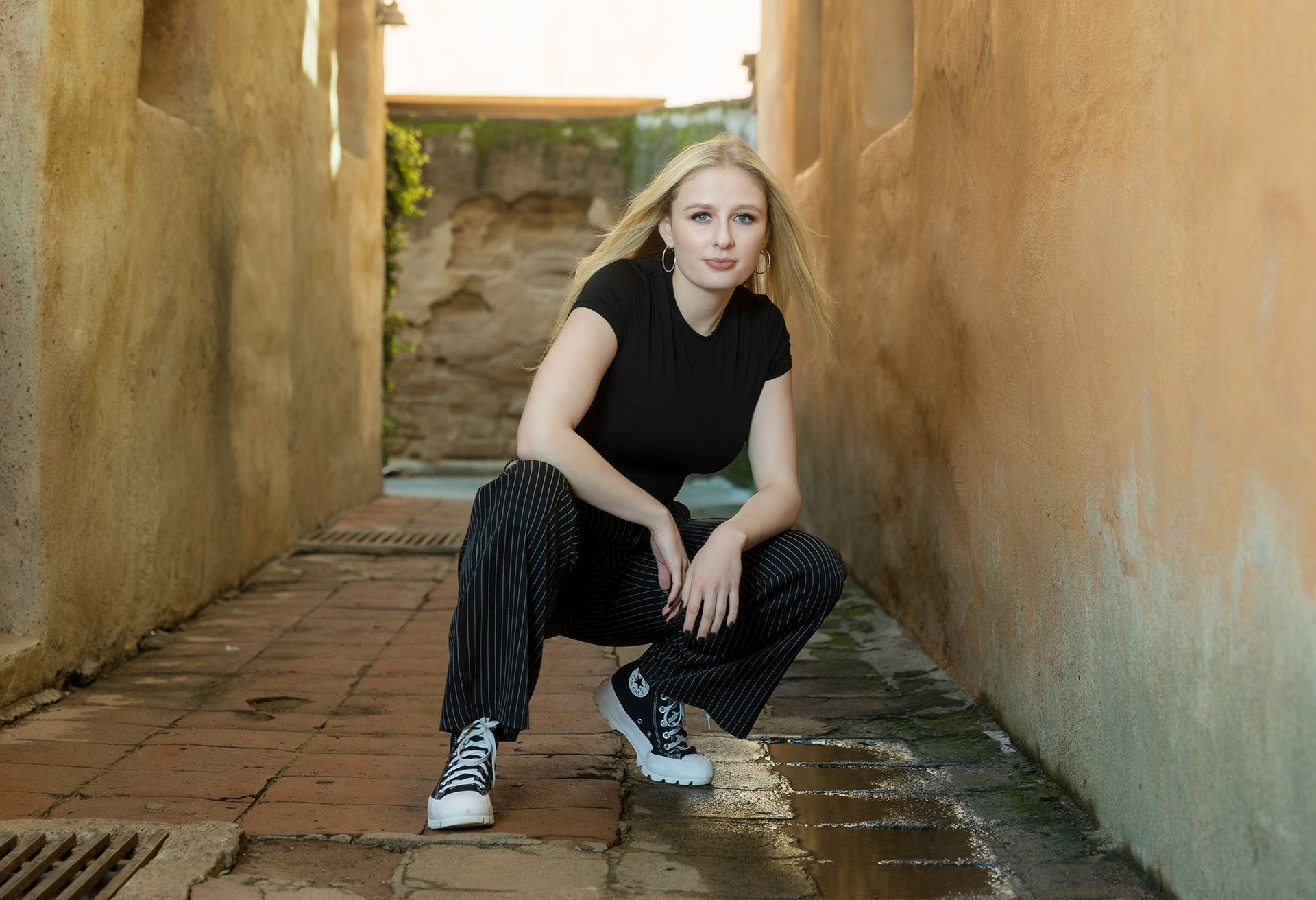 Senior girl seated in an adobe corridor at Mission San Juan Capistrano