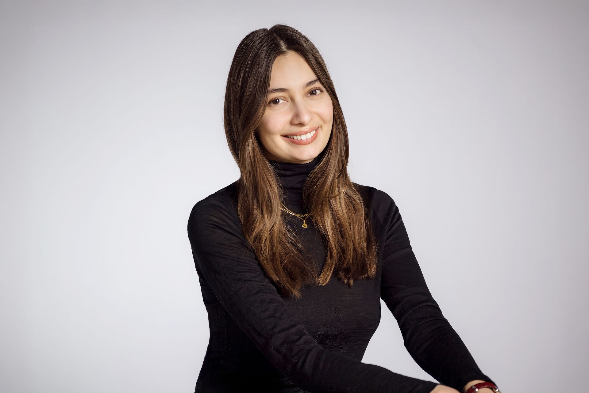 The woman is wearing a black turtleneck and smiling for the camera.