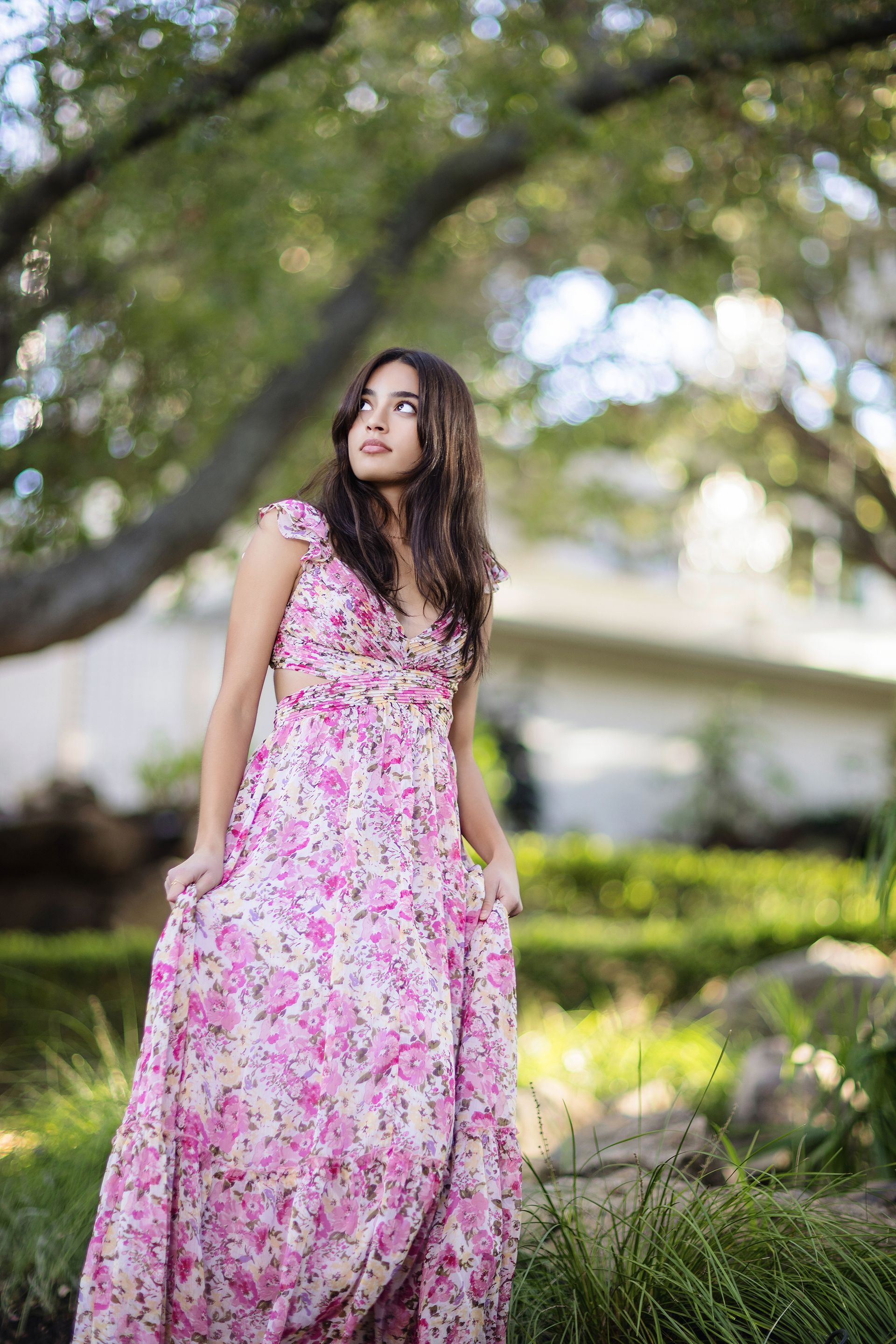 Senior girl in a pink floral maxi dress under the trees near the Upper Newport Back Bay