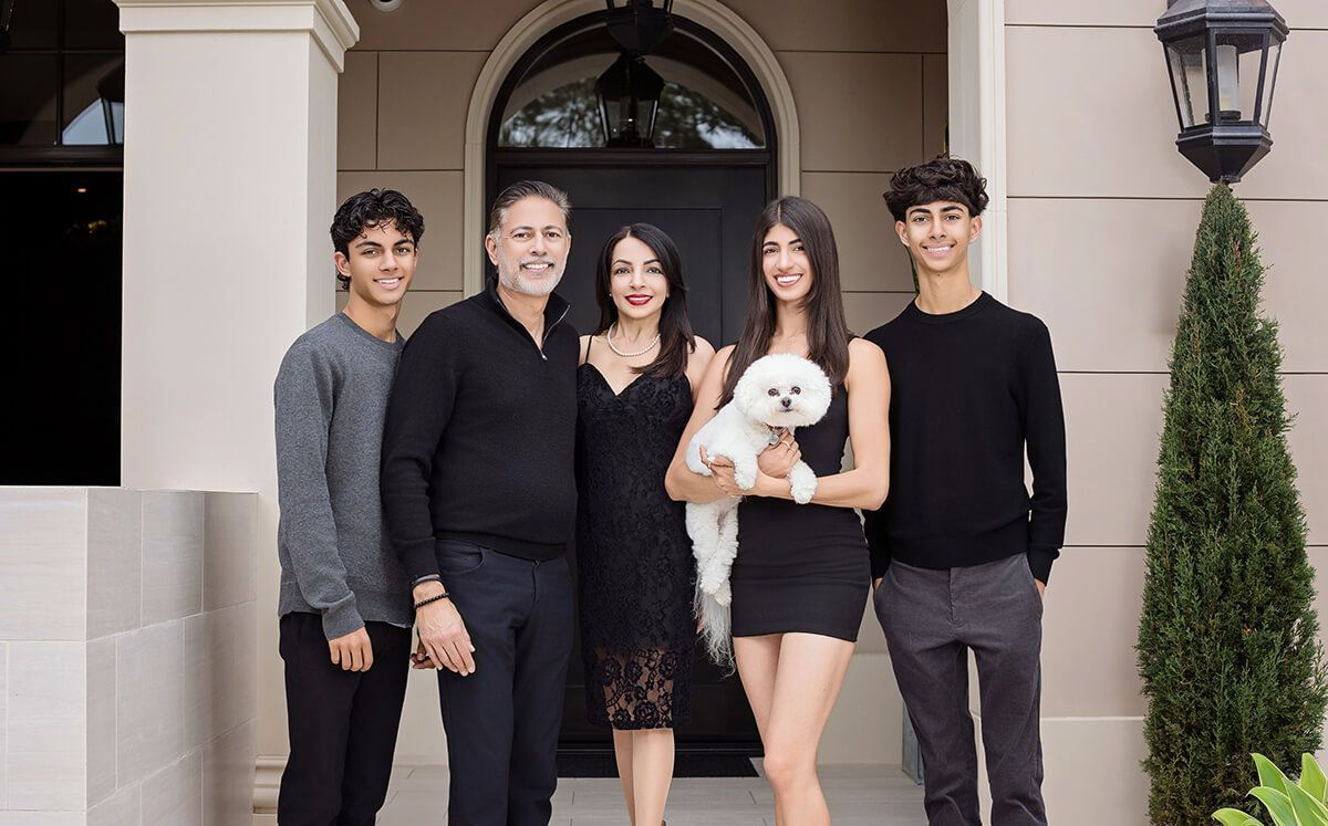 Elegant family portrait with a white poodle, captured during a luxury outdoor photo session by Orange County family photographer Blue Sky's Studio.