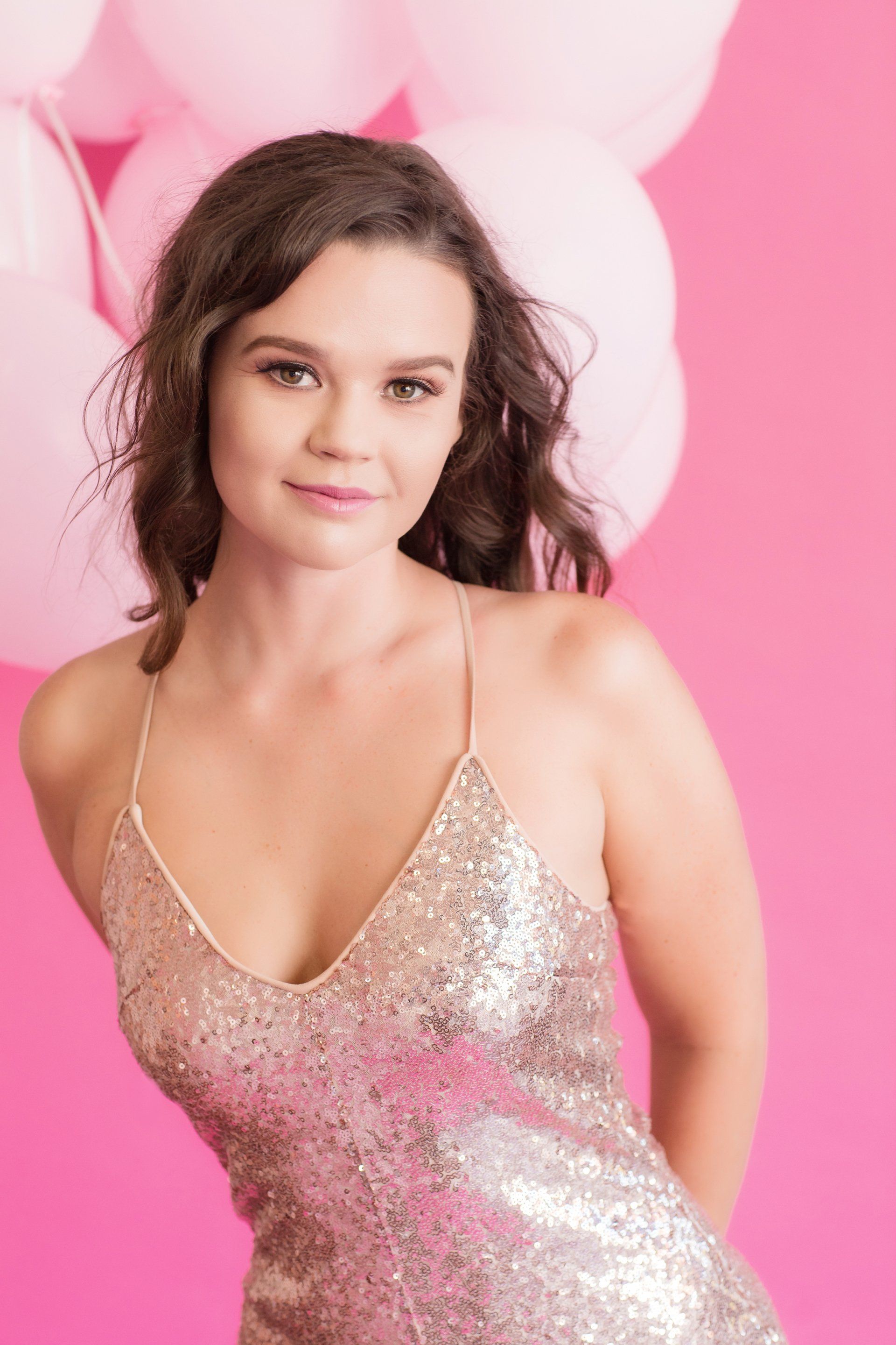 Photographer branding portrait in a sequin dress on a pink backdrop