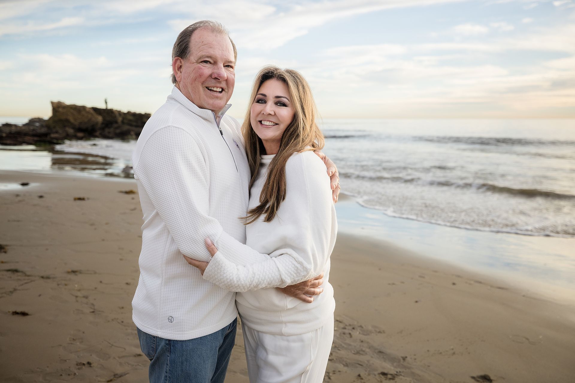 Grandparents wearing white outfit on the beach at sunset at Heisler Park in Laguna Beach