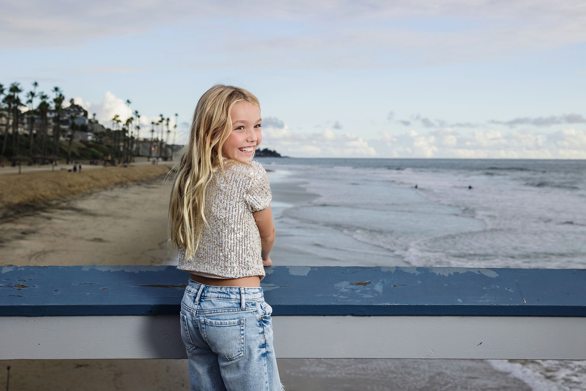 Girl looking out over the beach and palm trees from the San Clemente Pier railing