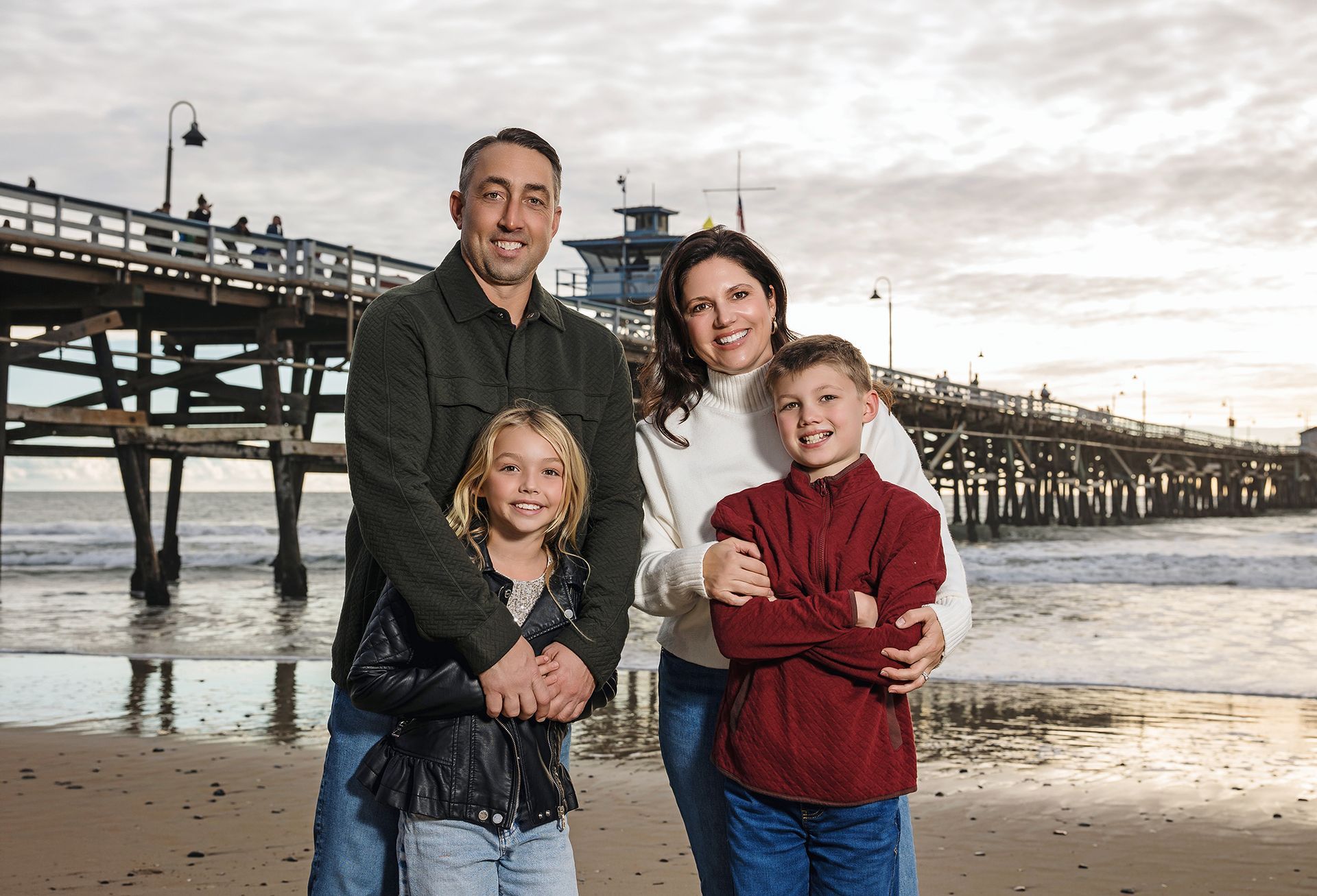 Family of four on the beach in front of the San Clemente Pier at sunset