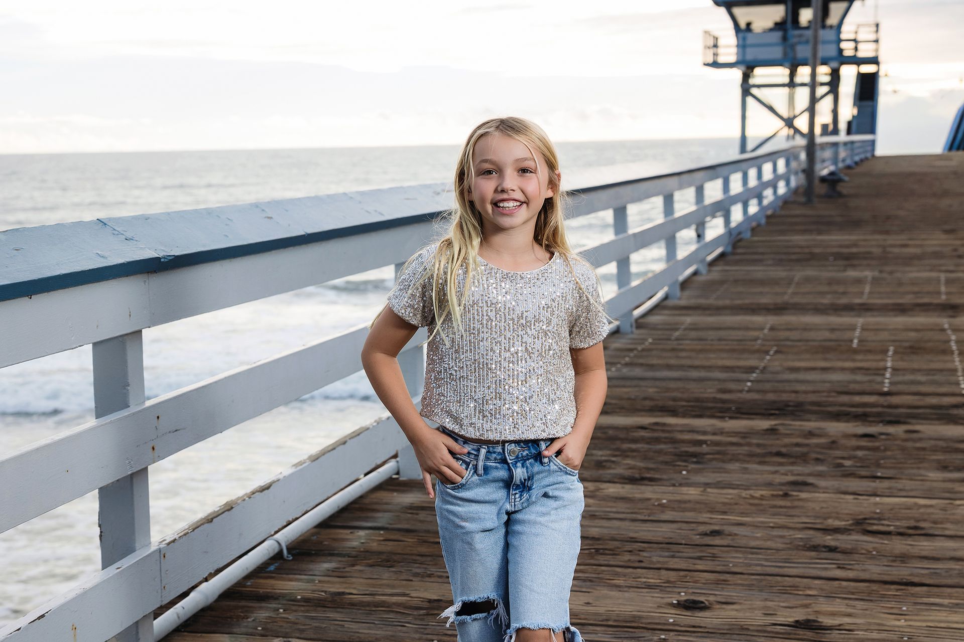 Smiling girl in a sequin top walking on the San Clemente Pier