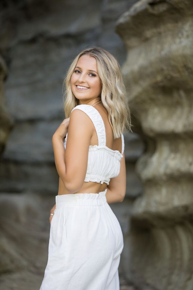 Senior girl in white against sandstone cliffs, Laguna Beach