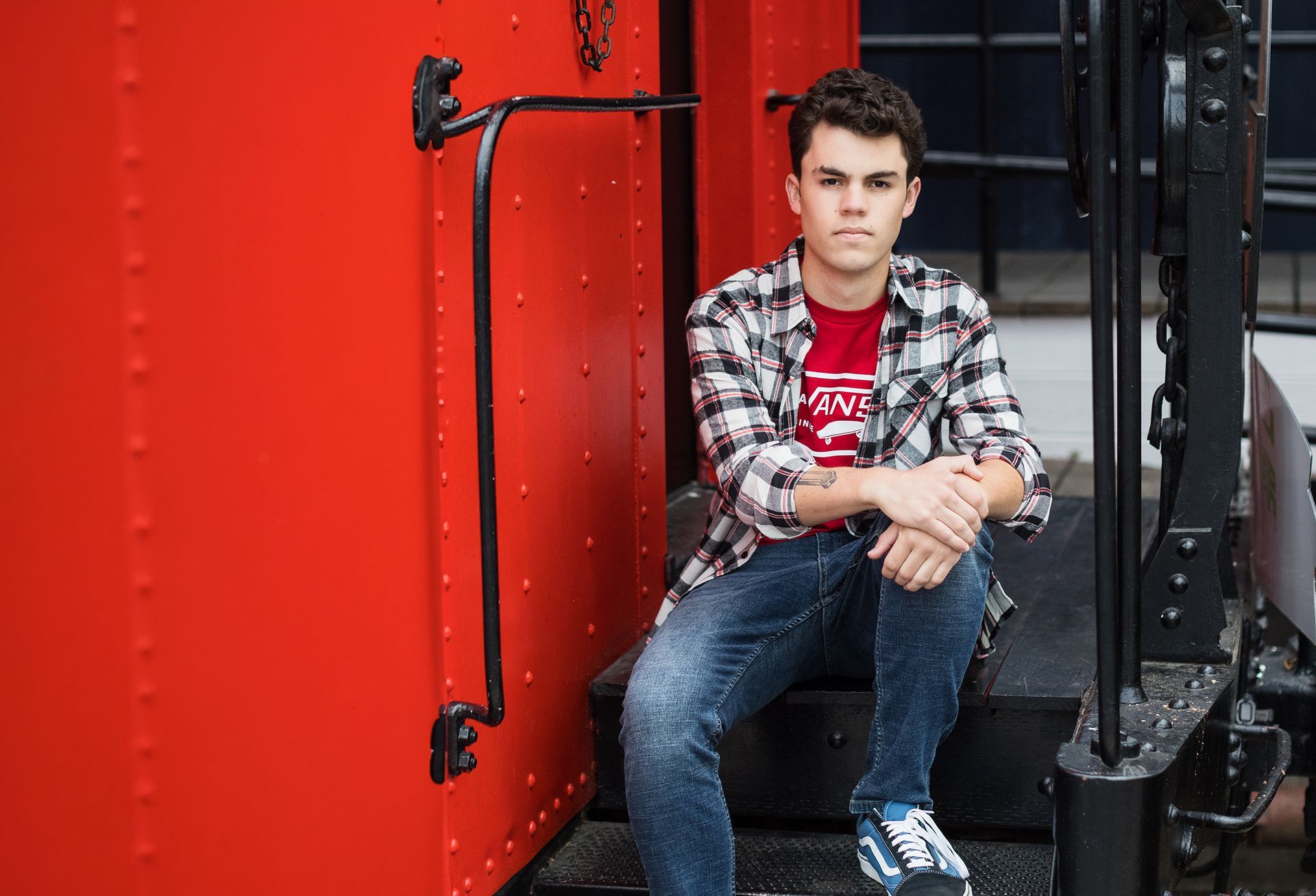 A young man is sitting on the steps of a train car.