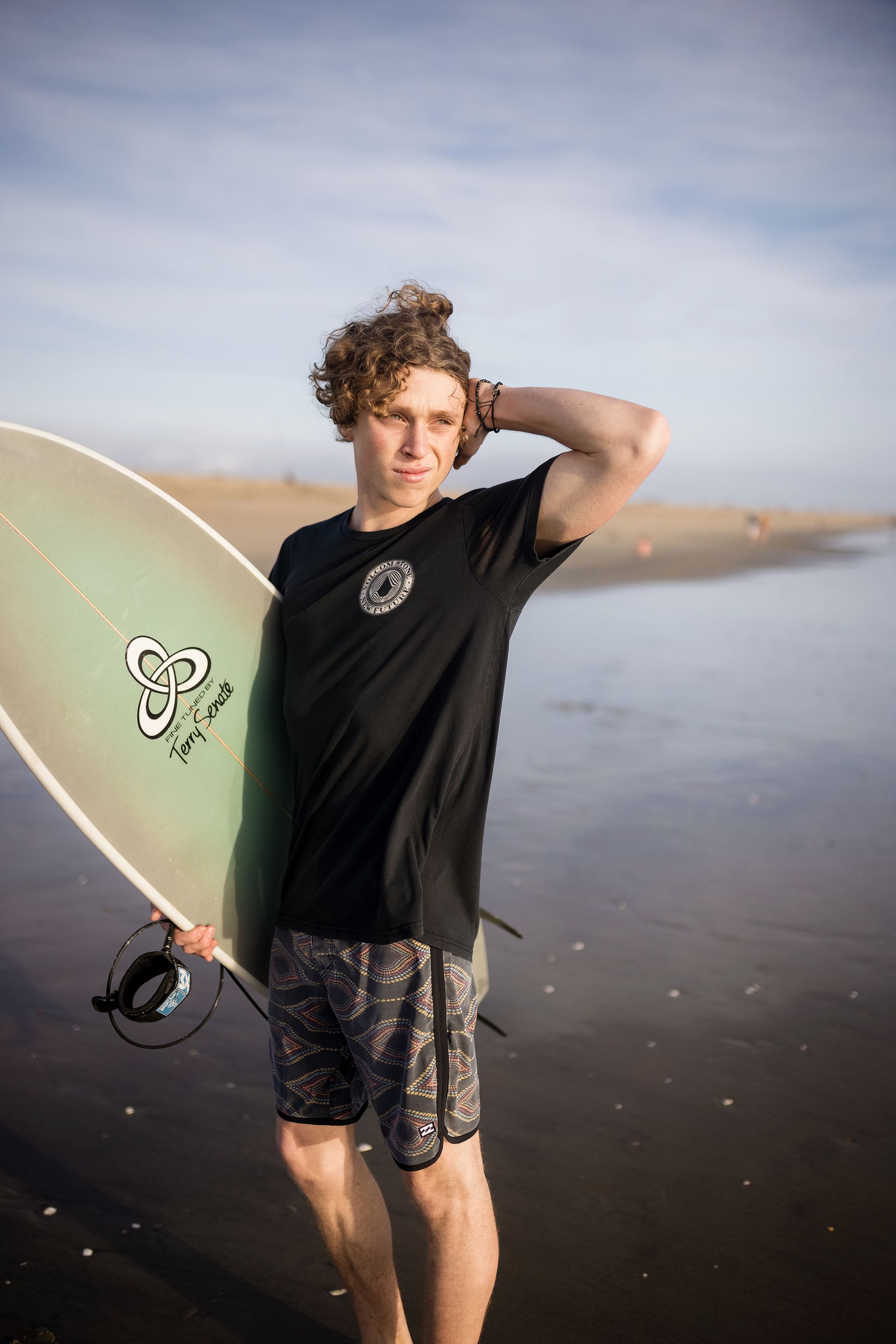 A young man is holding a surfboard on the beach.