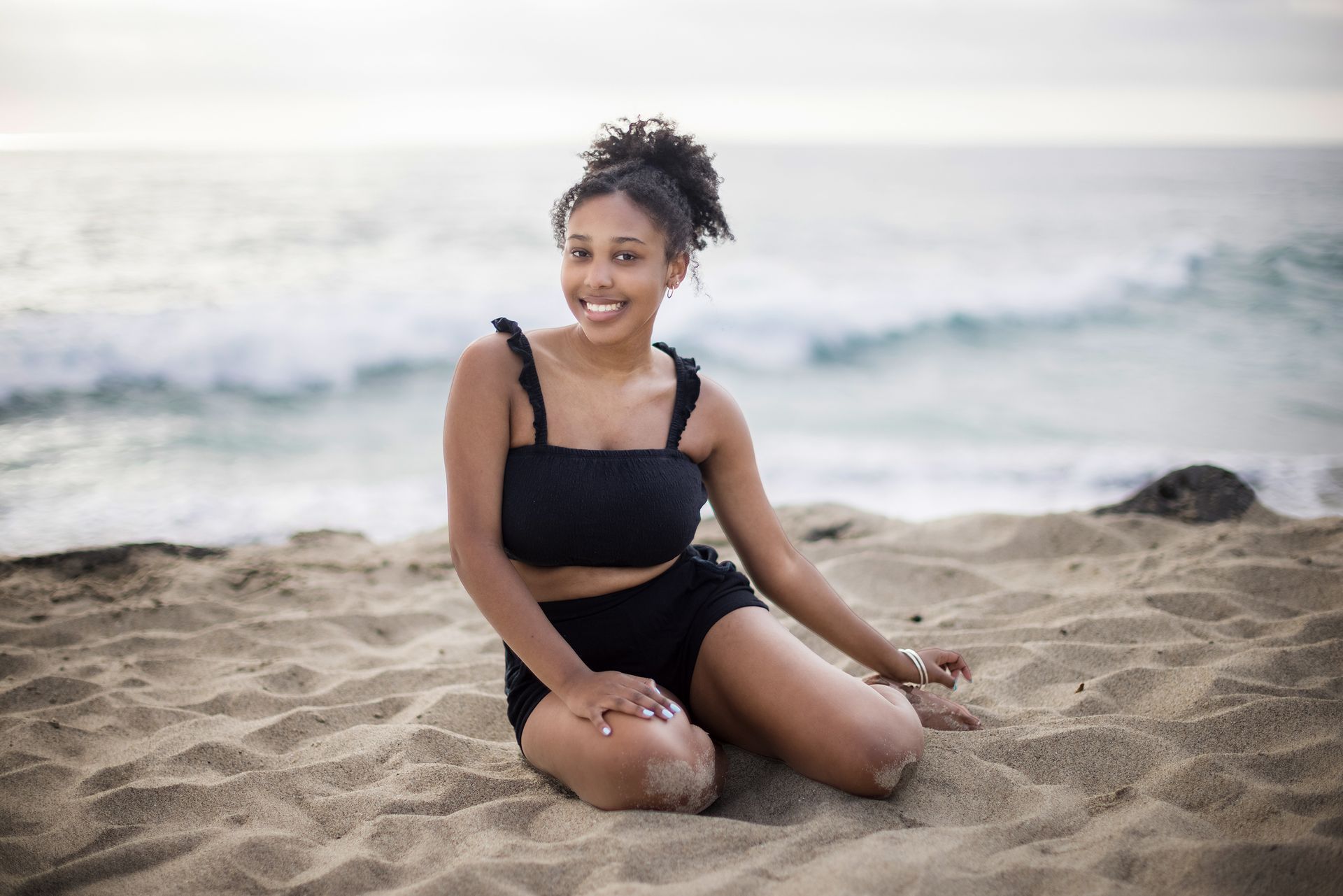 A woman in a bikini is sitting on the beach.