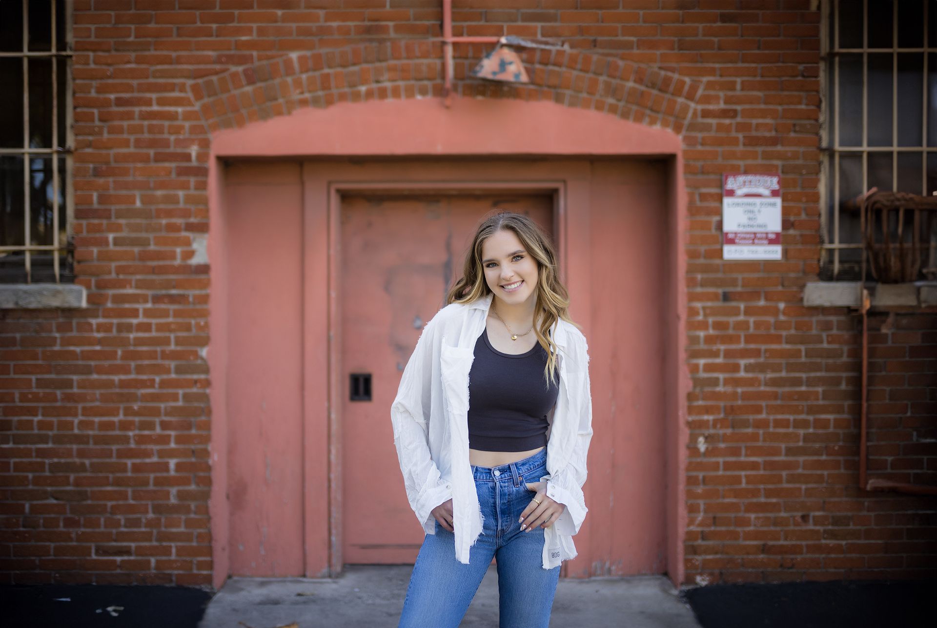 A woman is standing in front of a red brick building.