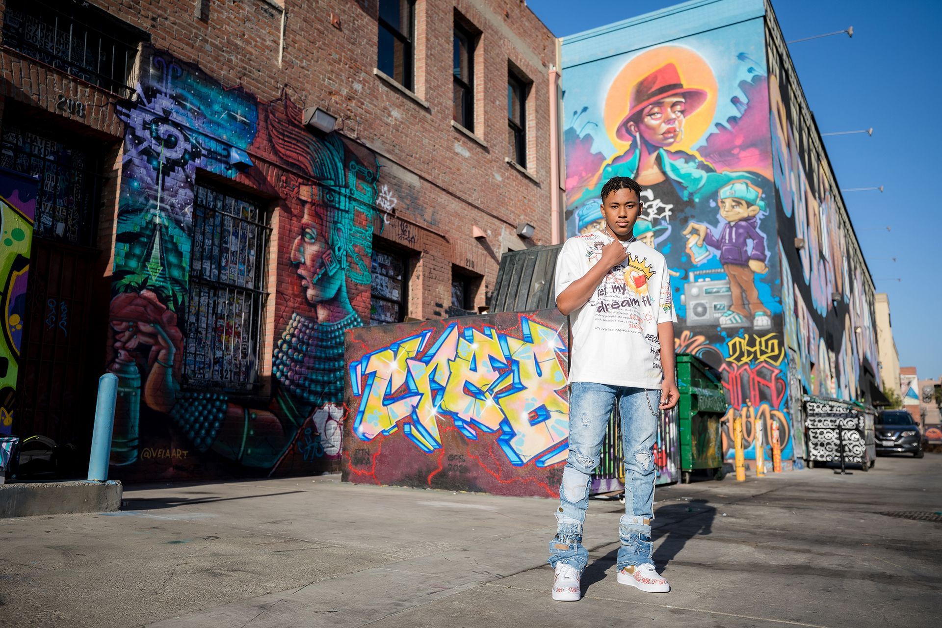 A man is standing in front of a building with graffiti on it.