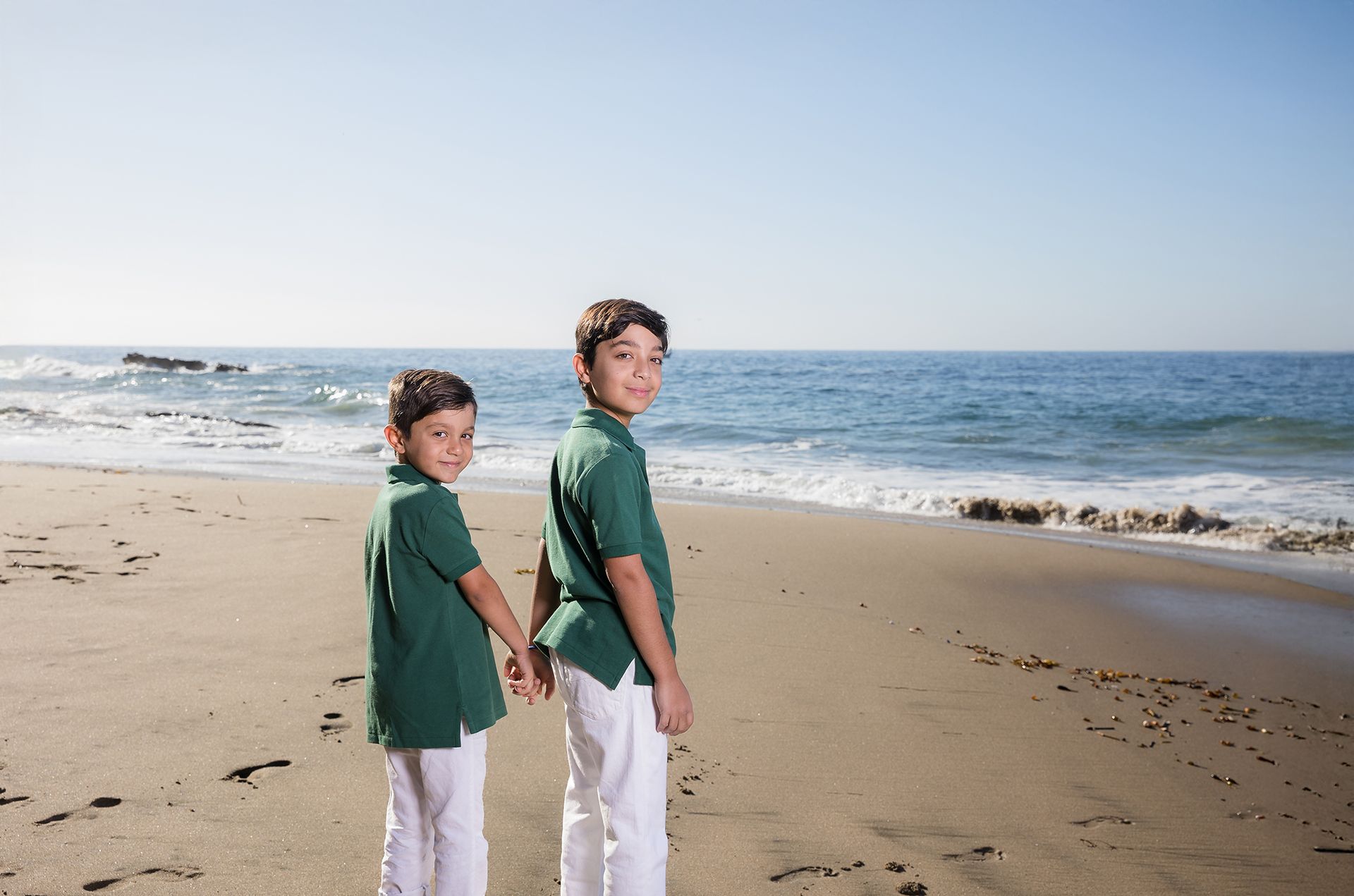 Beautiful early morning light for a Laguna Beach family photo shoot at sunrise of two brothers holding hands at the seashore.