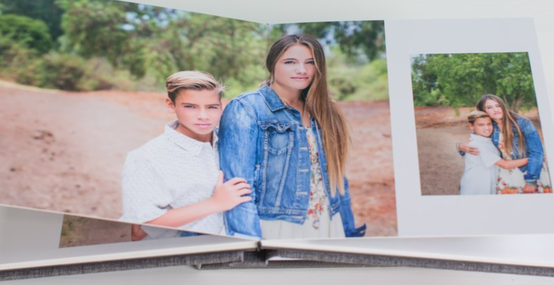 Open hand-bound family album showing sibling portraits