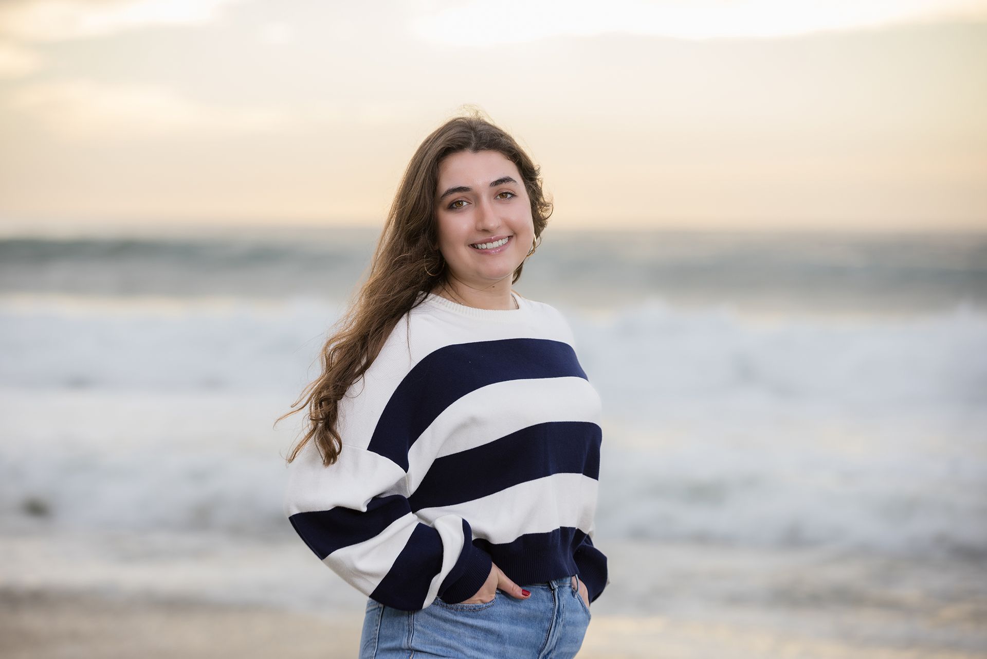 Girl in a navy striped sweater and jeans posing in front of the ocean at Salt Creek Beach at sunset.