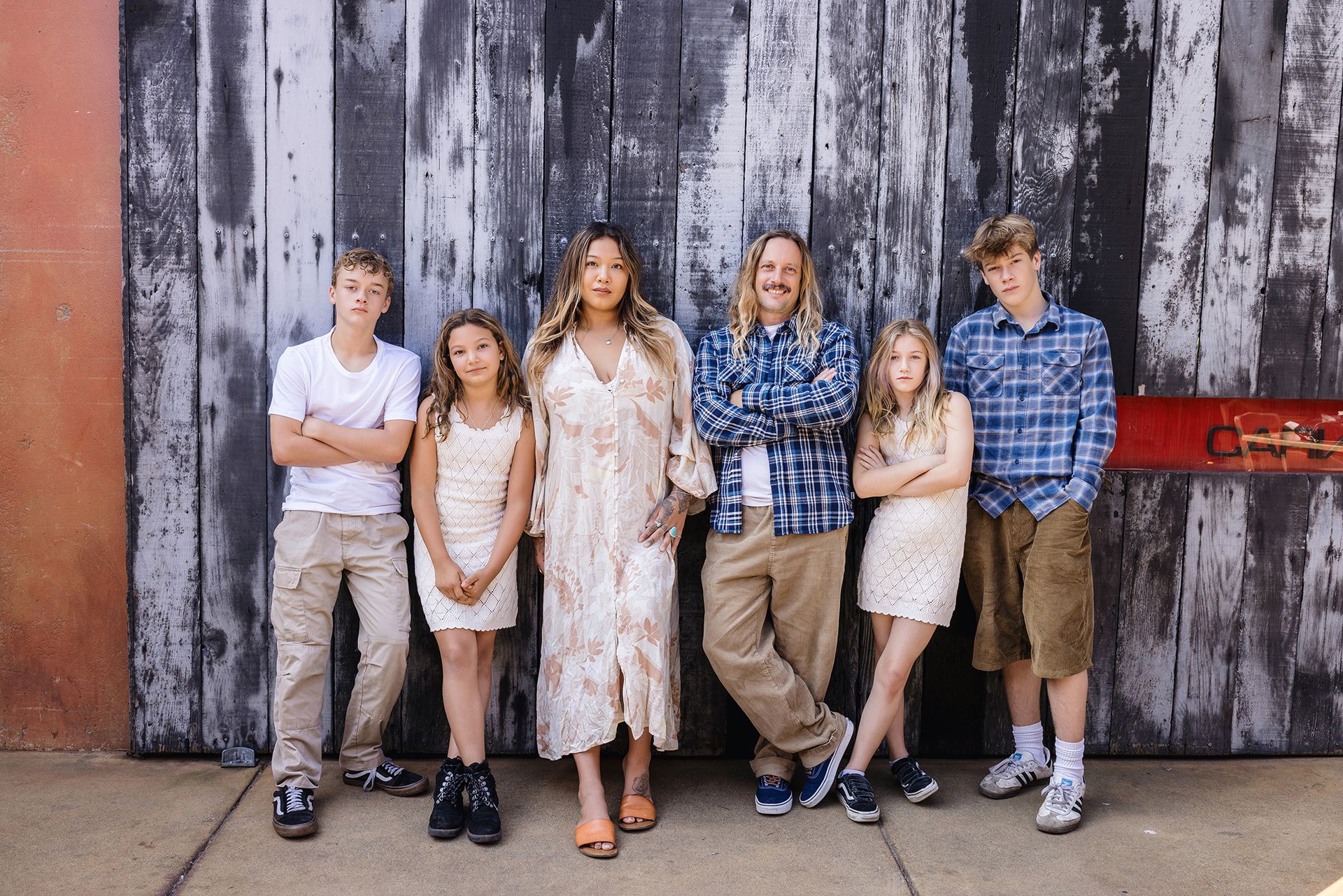 Family leaning against a weathered wood wall at The LAB Anti-Mall, Costa Mesa