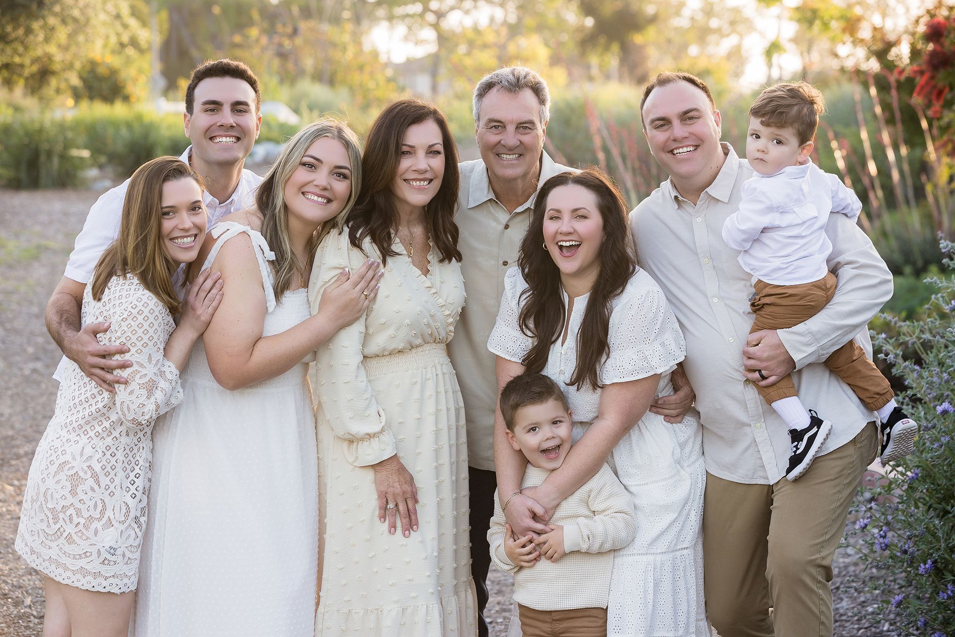 Laughing extended family in cream and white in golden light at the Huntington Beach Urban Forest