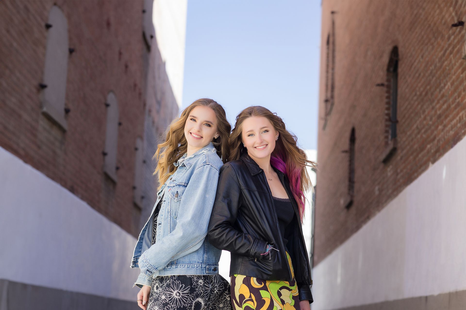 Two young women are standing next to each other in an alleyway.