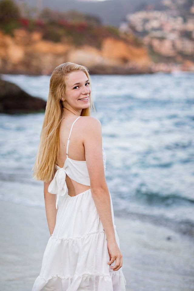 Senior girl in a white dress at the water’s edge, Laguna Beach