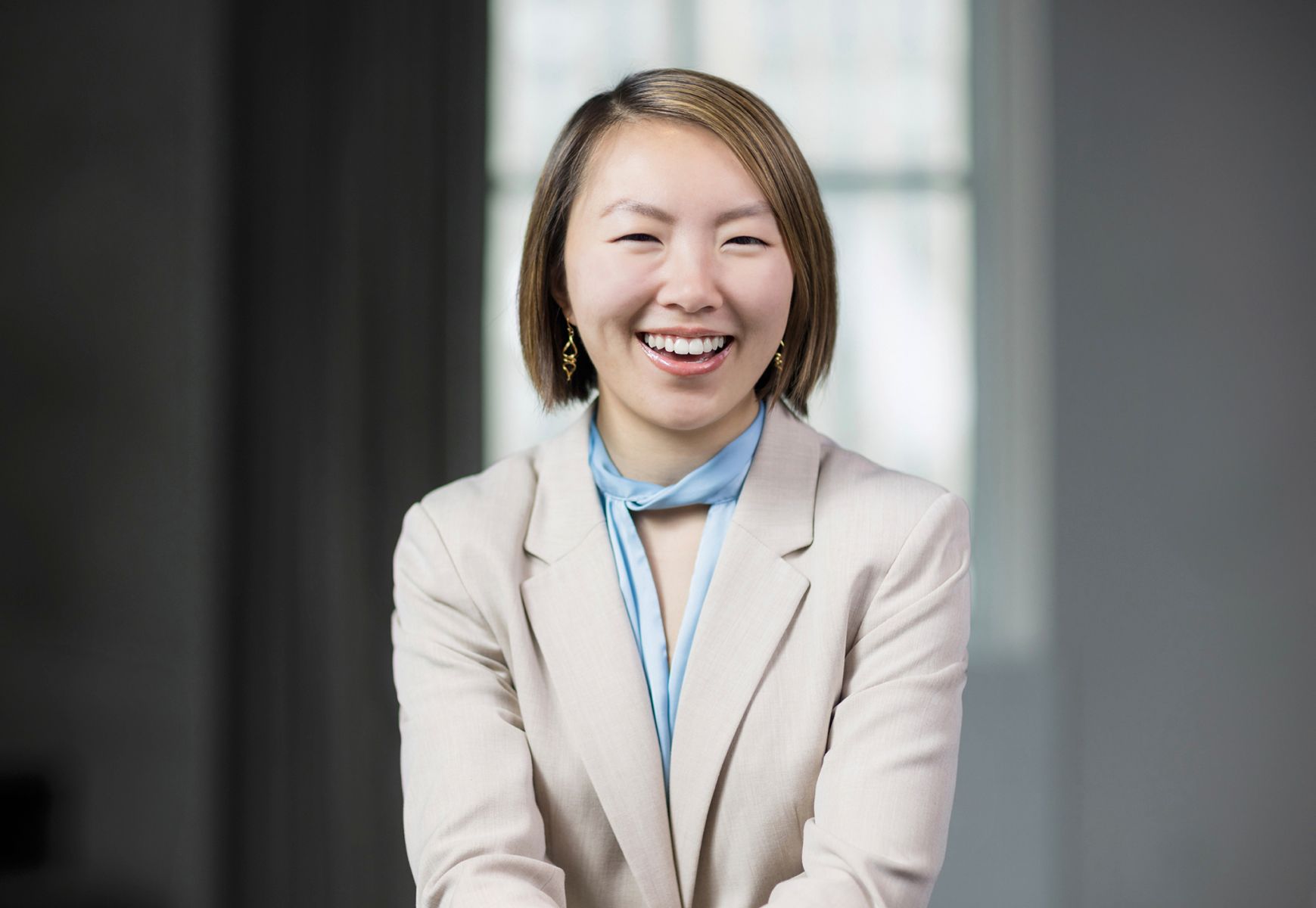 A woman in a suit and scarf is smiling for the camera.