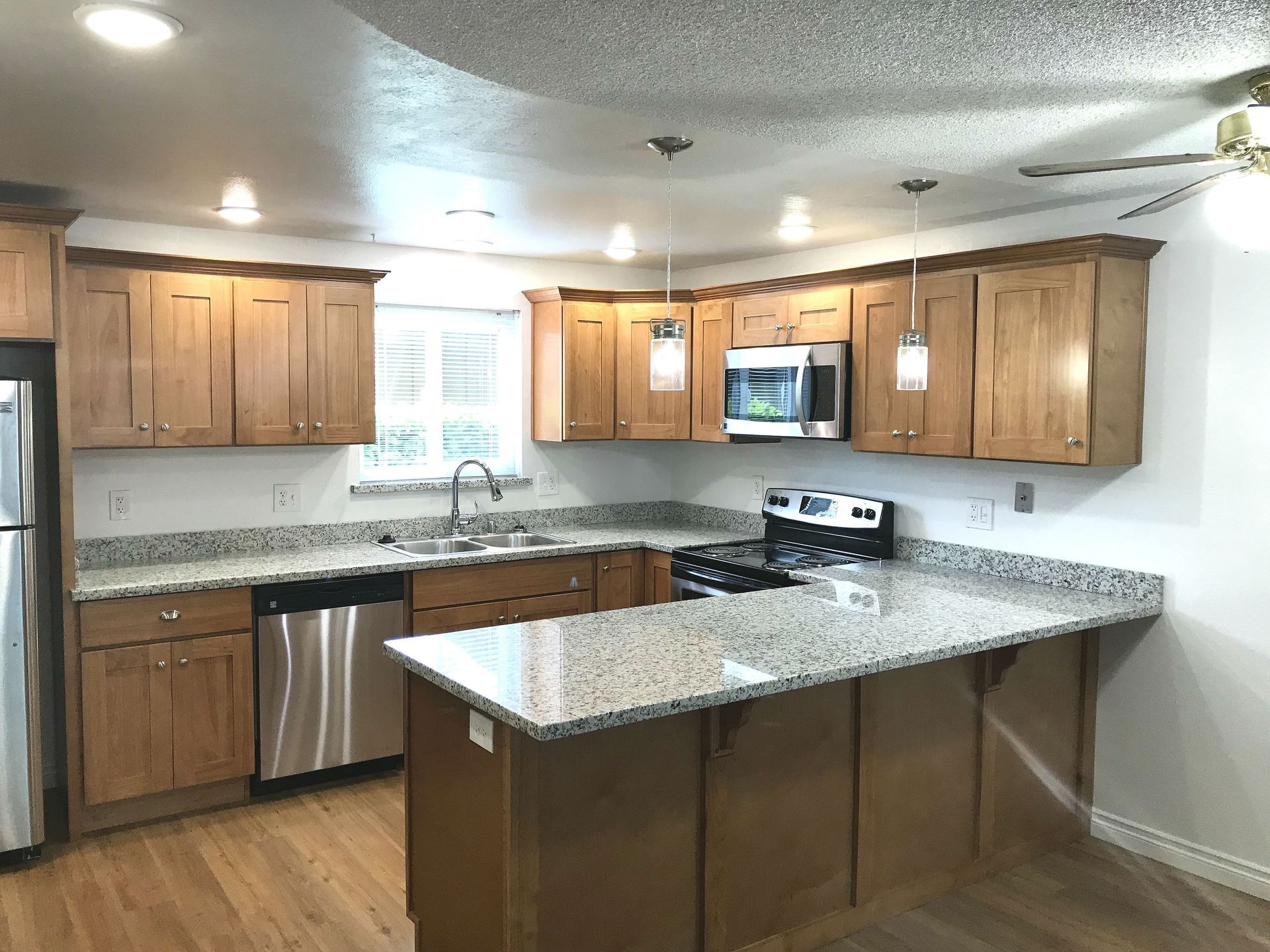Kitchen with light wood cabinets, granite countertops, stainless steel appliances, and island.