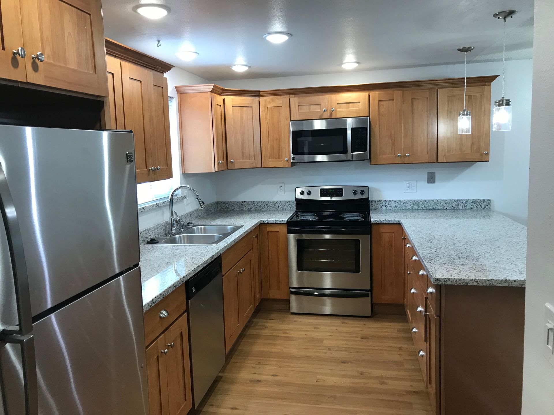 U-shaped kitchen with wood cabinets, stainless steel appliances, and granite countertops.