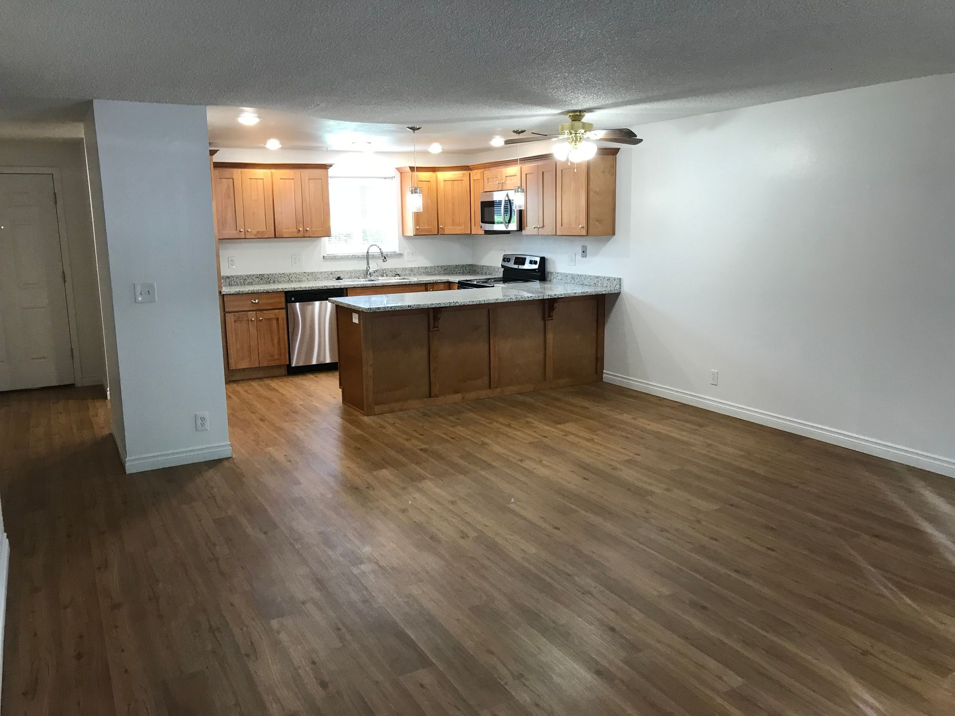 Kitchen with wood cabinets, granite countertops, and wooden floor.