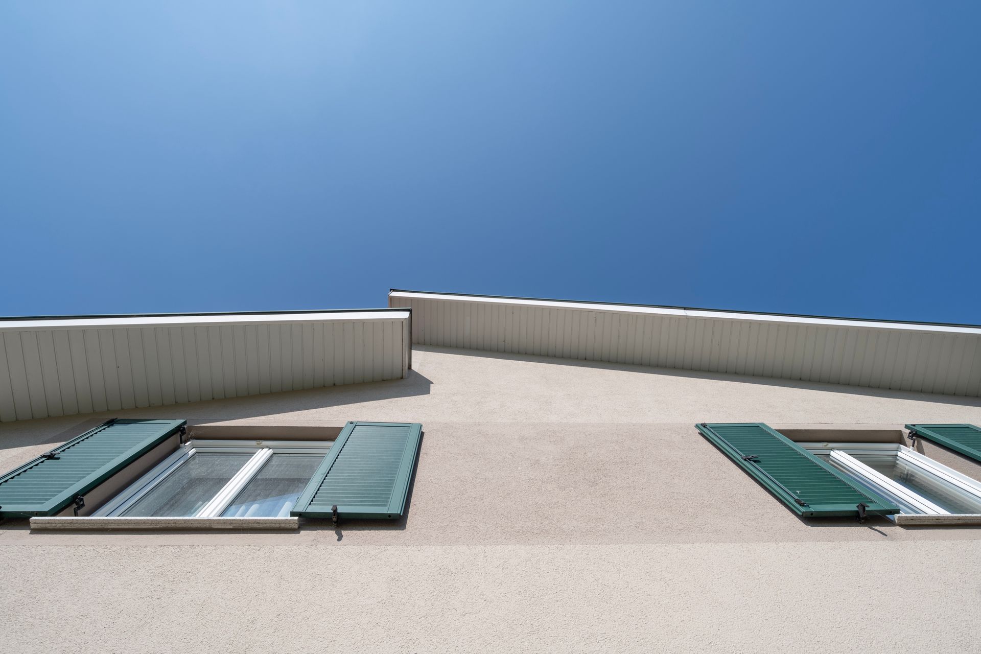 ein Gebäude mit zwei Fenstern und grünen Fensterläden