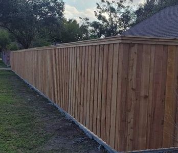 Wooden privacy fence along a yard, with dark posts and a sloped roof visible behind it.