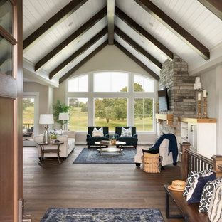 Bright vaulted living room with exposed beams, large windows, fireplace, and modern seating over a dark wood floor