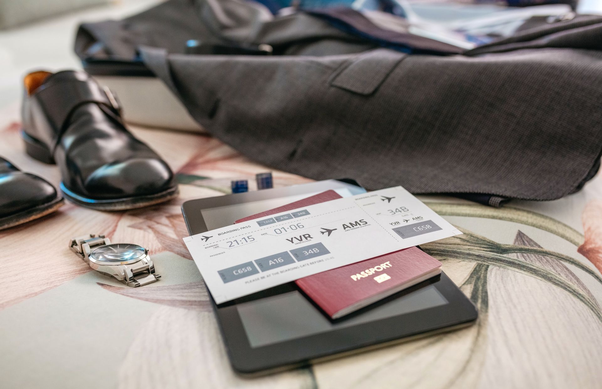 Suitcase, shoes, and tablet with ticket and passport.