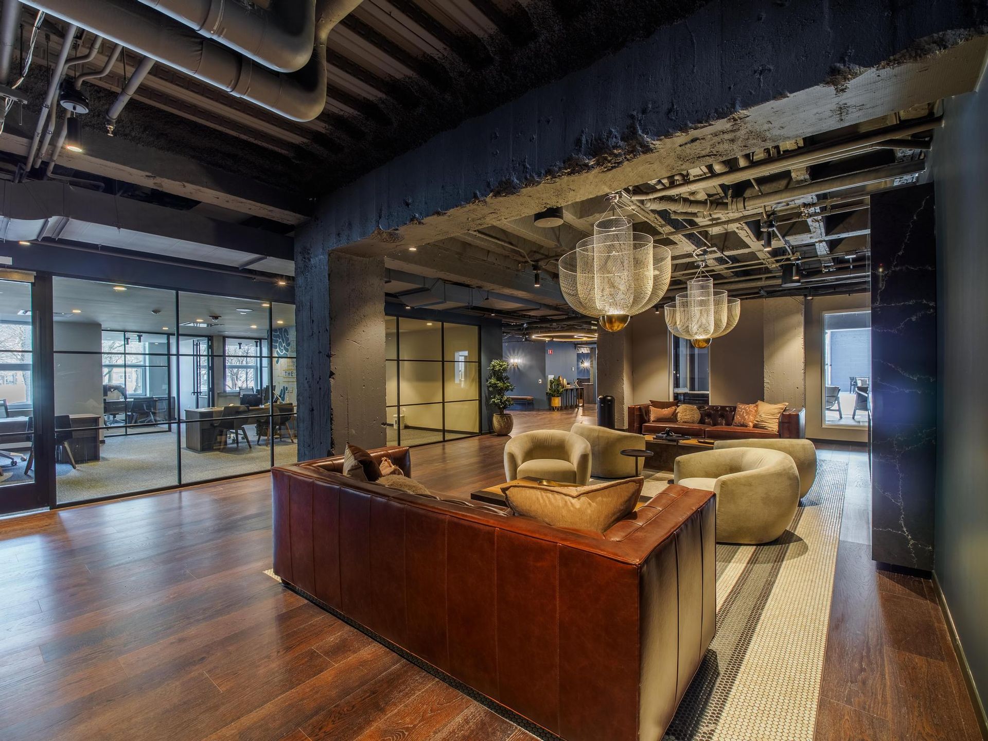 A living room at The Thompson with a couch , chairs , and chandeliers.