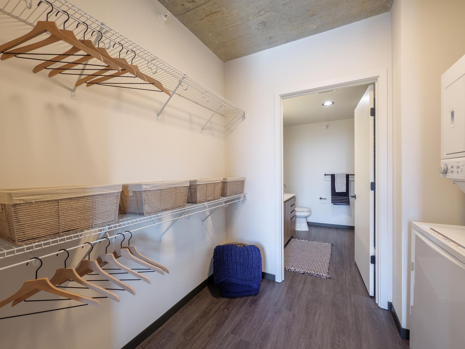 spacious closet with shelving and a stacked washer and dryer, leading to a bathroom