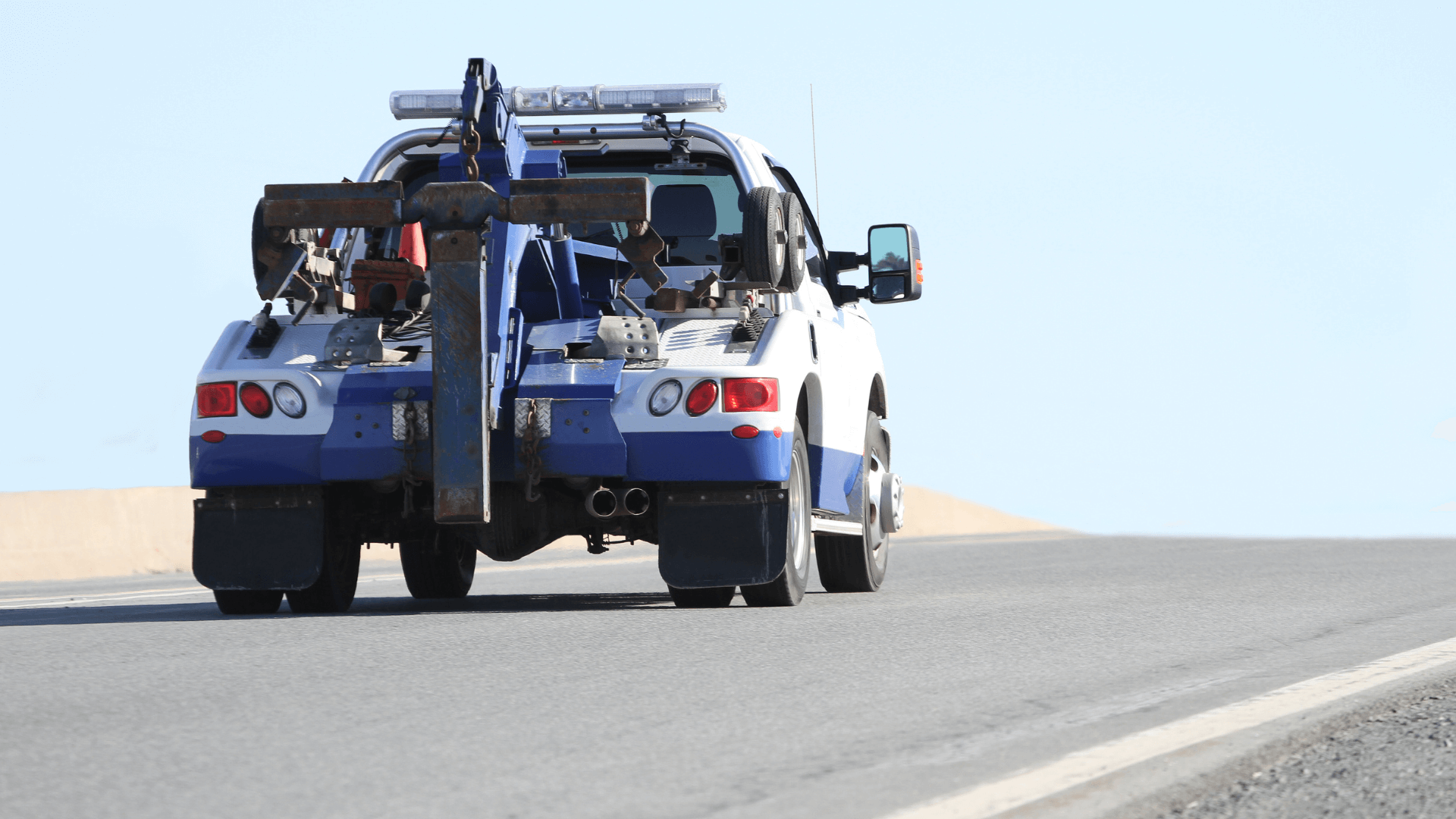 Local tow truck hauls a flatbed car away from city in harper woods