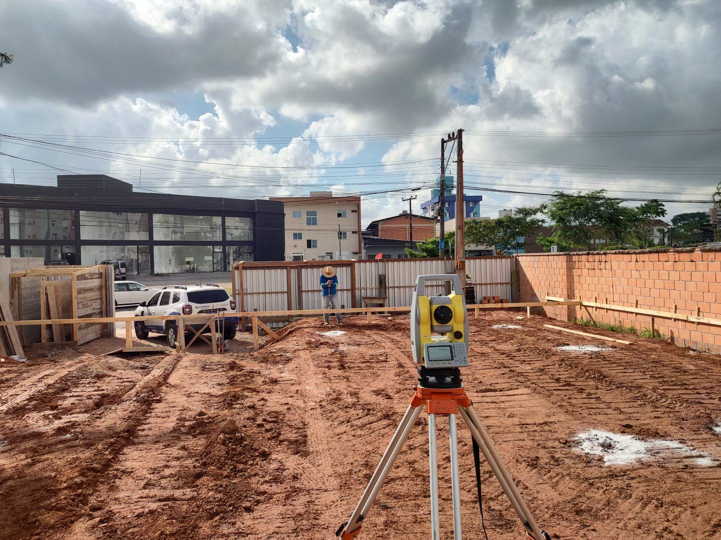 A total station is sitting in the middle of a dirt field.