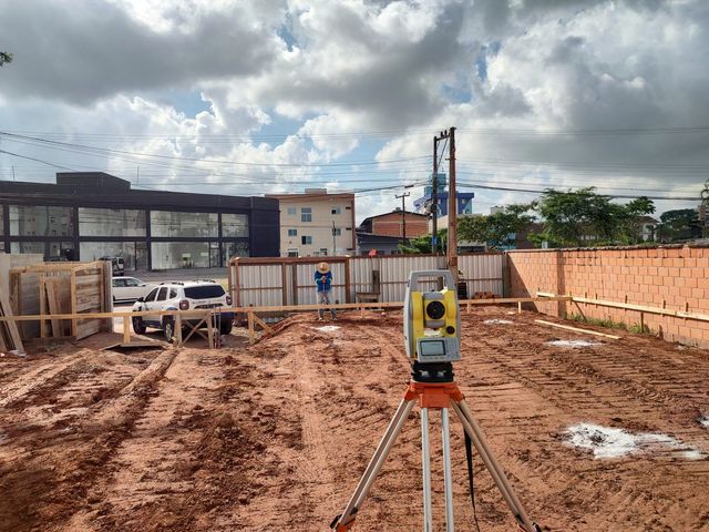 A total station is sitting in the middle of a dirt field.