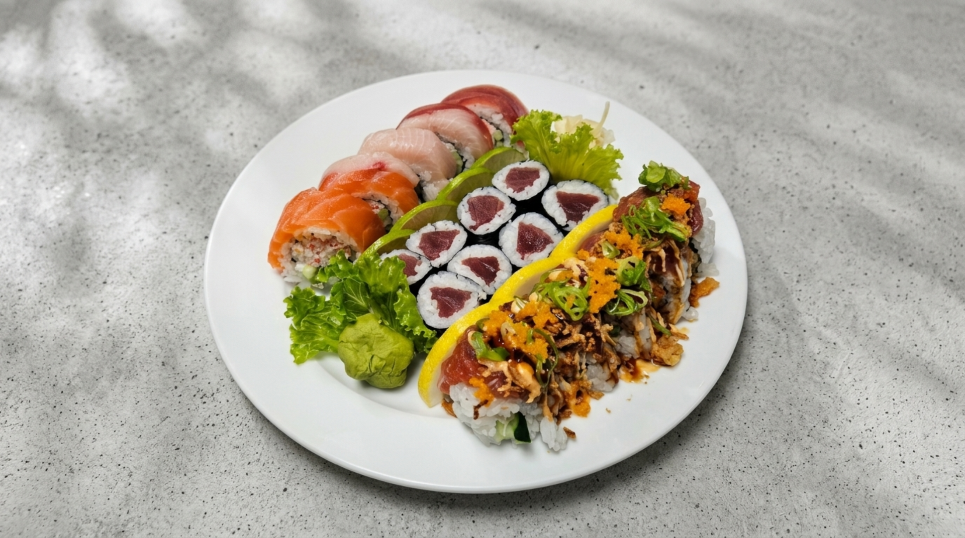 Sushi platter with salmon nigiri, maki rolls, and a colorful rice dish on a white plate