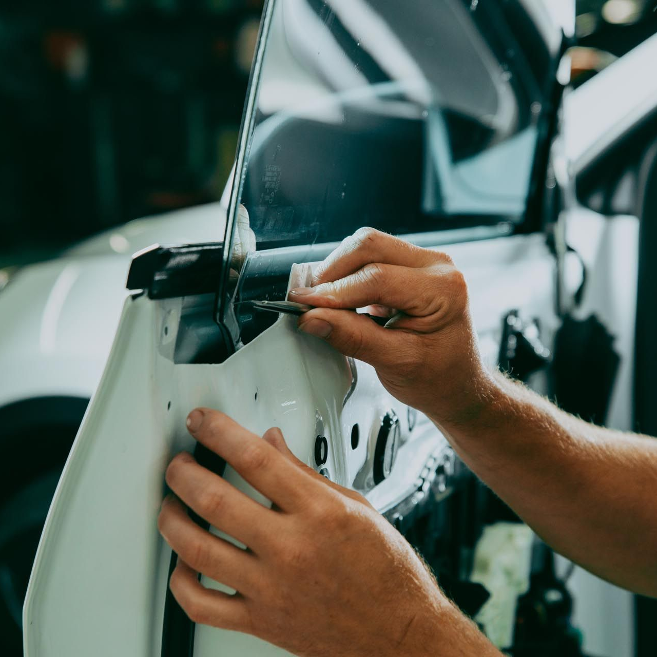 A person is cleaning a blue car with an orange towel