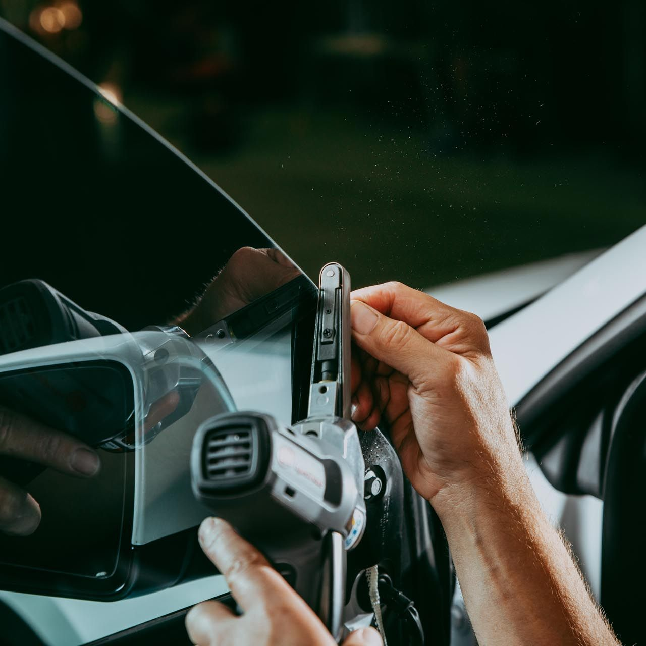 A person is cleaning a blue car with an orange towel