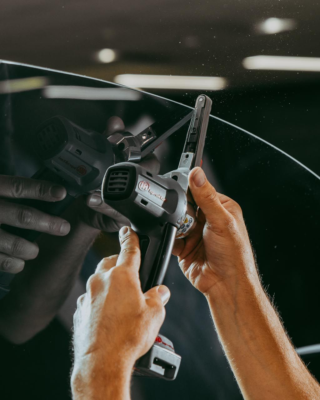 A person is applying a clear film to the hood of a car.