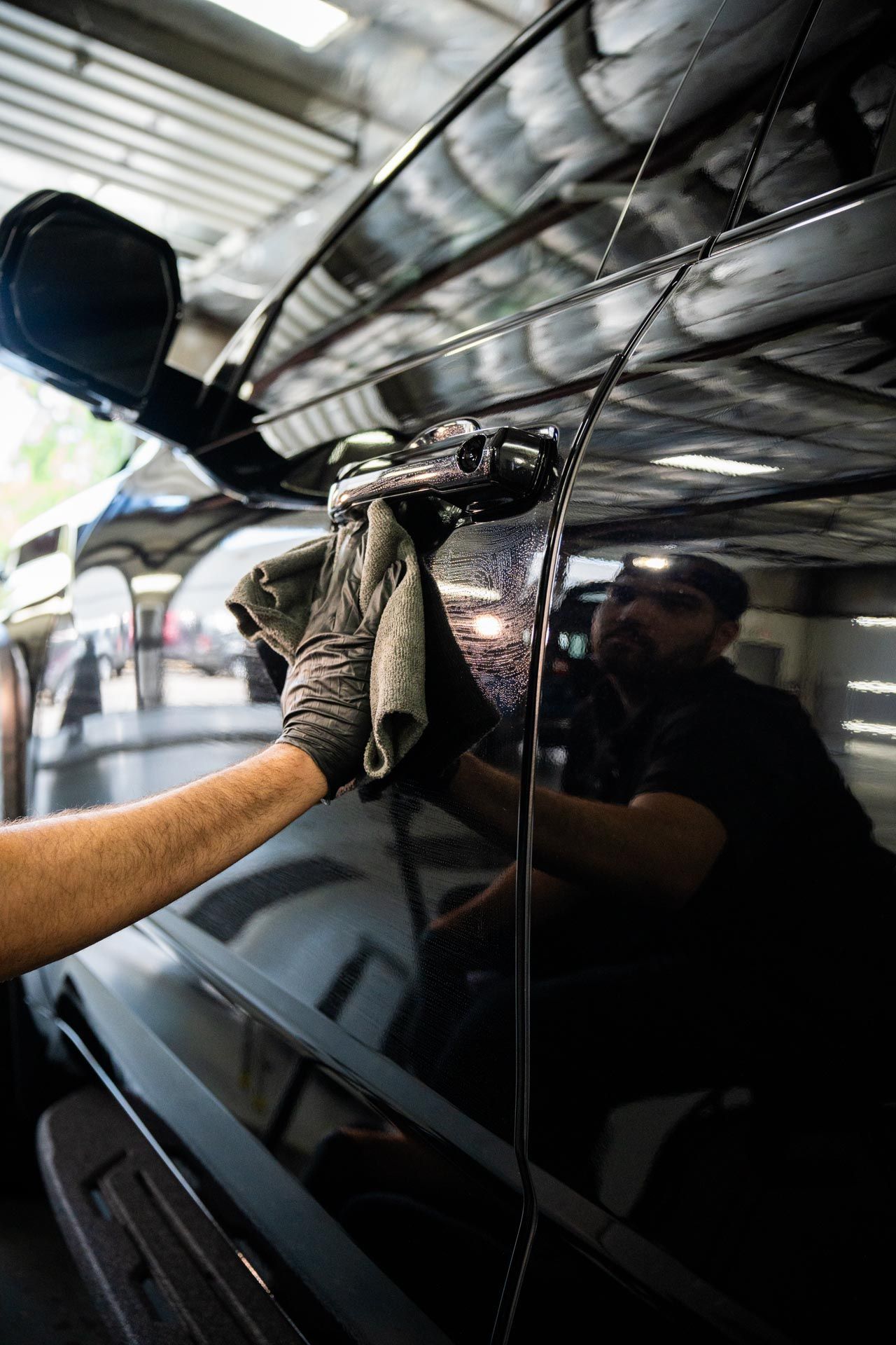 A man is cleaning the wheel of a black car with a sponge.