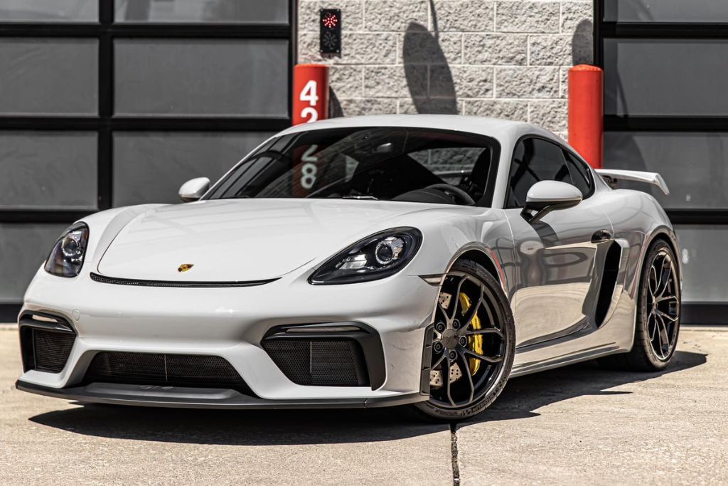 A white luxury sports car parked outdoors, showcasing a glossy, pristine paint finish and polished black alloy wheels, protected by paint protection film.