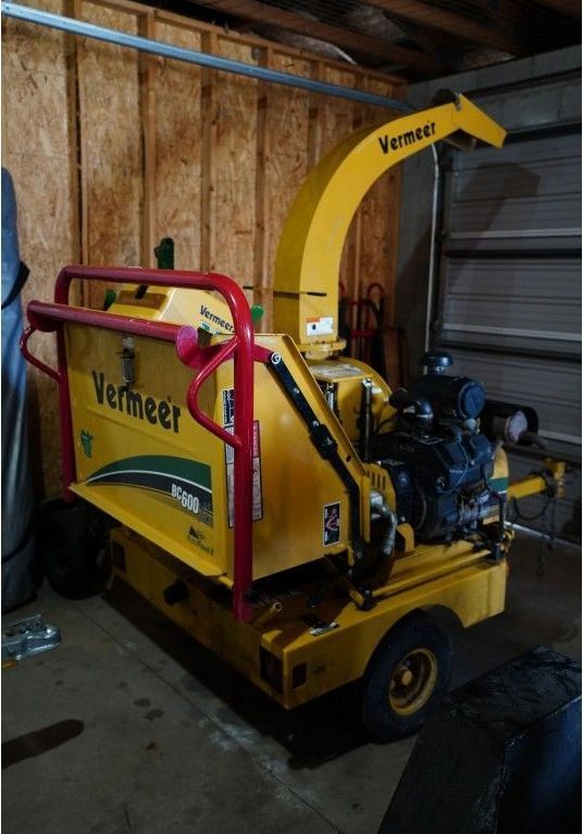 Yellow Vermeer wood chipper parked in a garage, side view with red railings and a black engine.