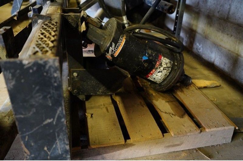 Industrial work boots and gear resting on a wooden pallet in a warehouse.