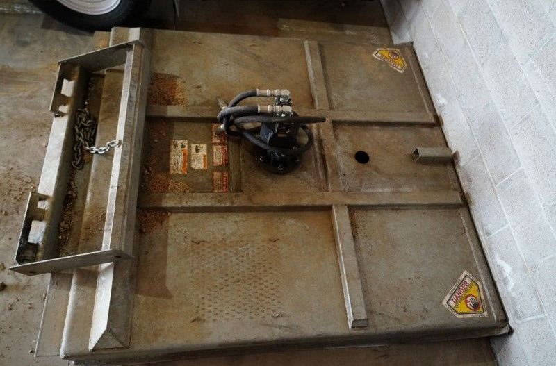 Industrial metal platform with a mounted motor, rusted surface, and a white wall background