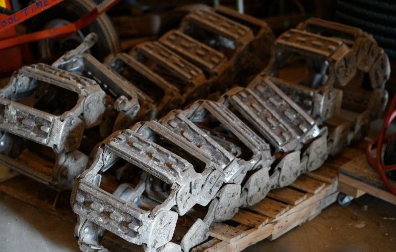 Several old, weathered metal robotic parts or tools stacked on wooden pallets in a workshop.