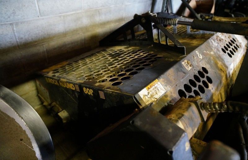 Rusty industrial machinery with perforated metal panels in a dim workshop