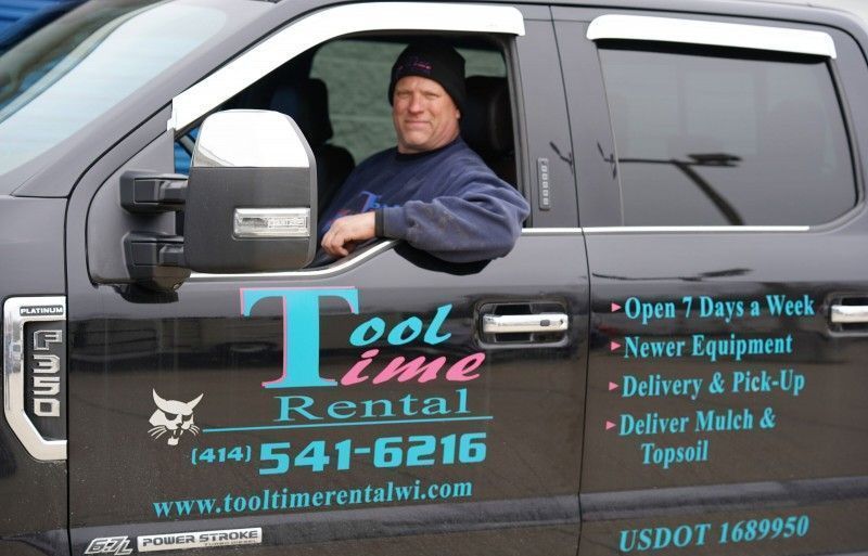 Tool Time Rentals service truck with contact info and driver at the wheel