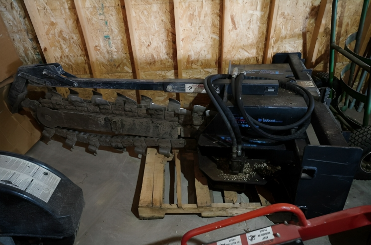 Heavy machinery parts on wooden pallets in a warehouse, including a black engine-like unit and coiled hose.