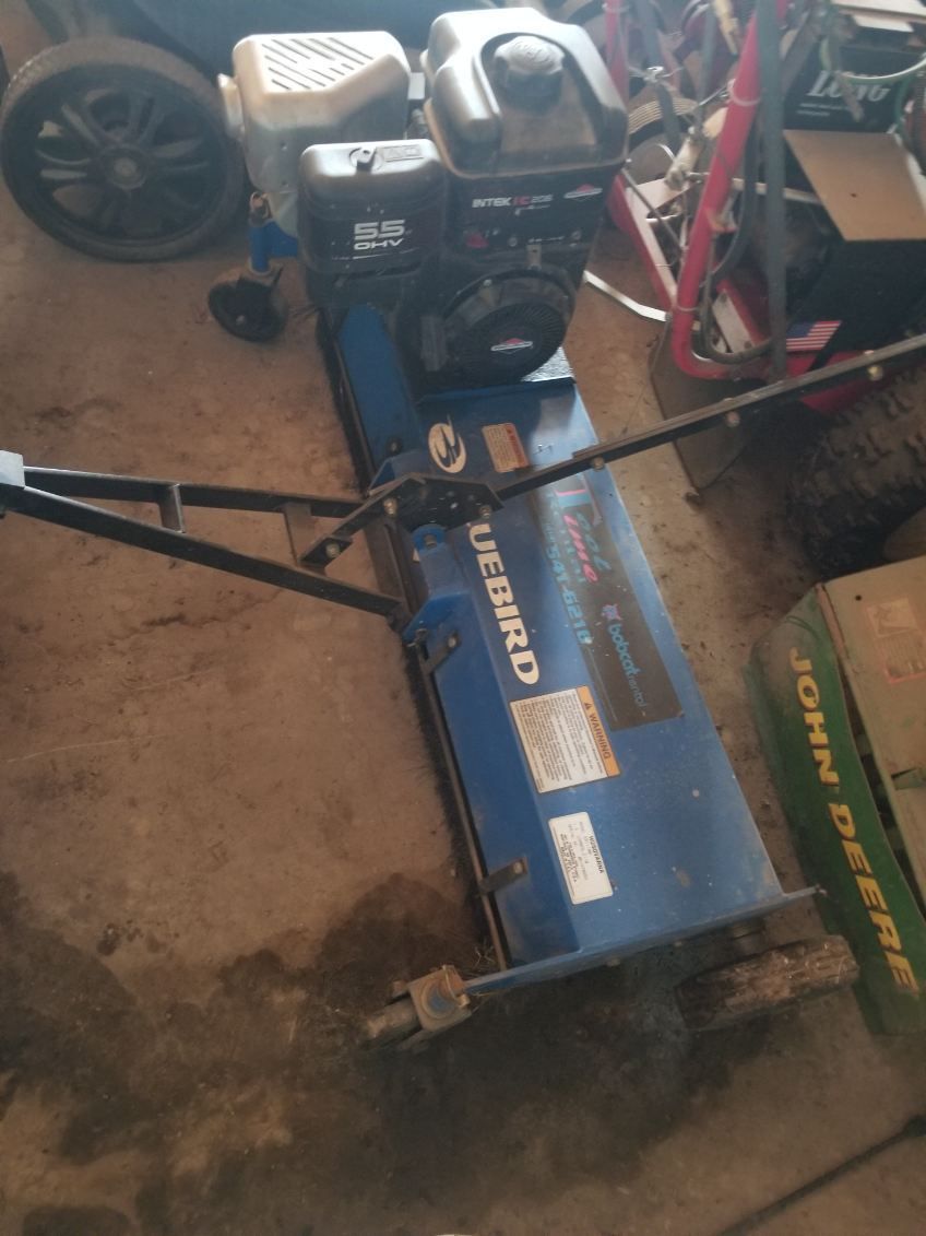 Blue Craftsman snow blower in a garage beside a black generator and red bicycle.