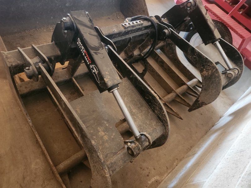 Dirty metal agricultural implement with tines and blades on a floor